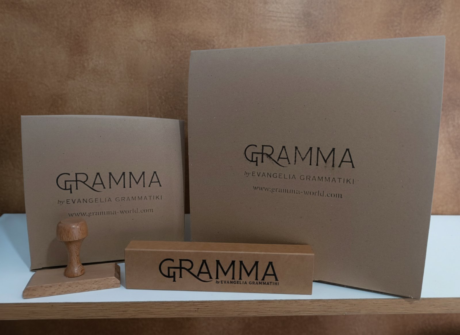 GRAMMA sustainable packaging boxes made of recycled kraft paper with branded logo by Evangelia Grammatiki and a wooden stamp.