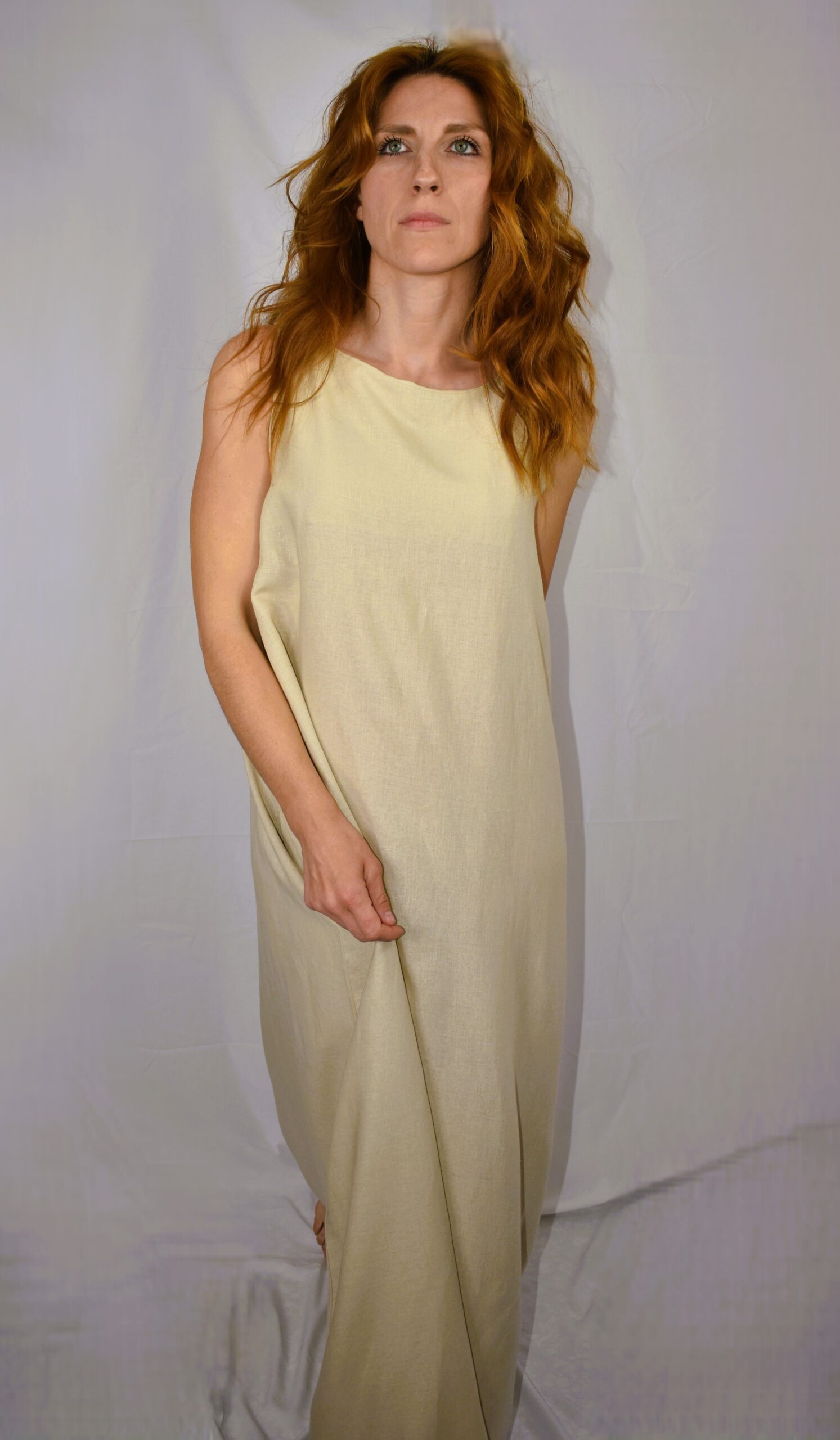 Close-up shot of the beige Isichastirio dress, emphasizing the natural flow of the fabric and the subtle handcrafted details on the hem.