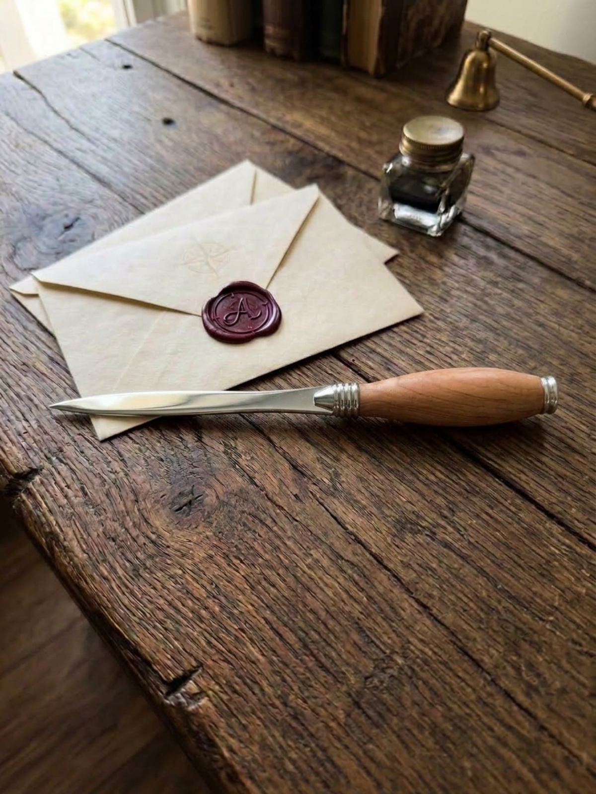 Χειροποίητος χαρτοκόπτης από ξύλο ελιάς με ασημένιες μεταλλικές λεπτομέρειες, τοποθετημένος σε ξύλινη επιφάνεια, συμβολίζοντας τον διαχωρισμό από το παρελθόν και το άνοιγμα μιας νέας διαδρομής.