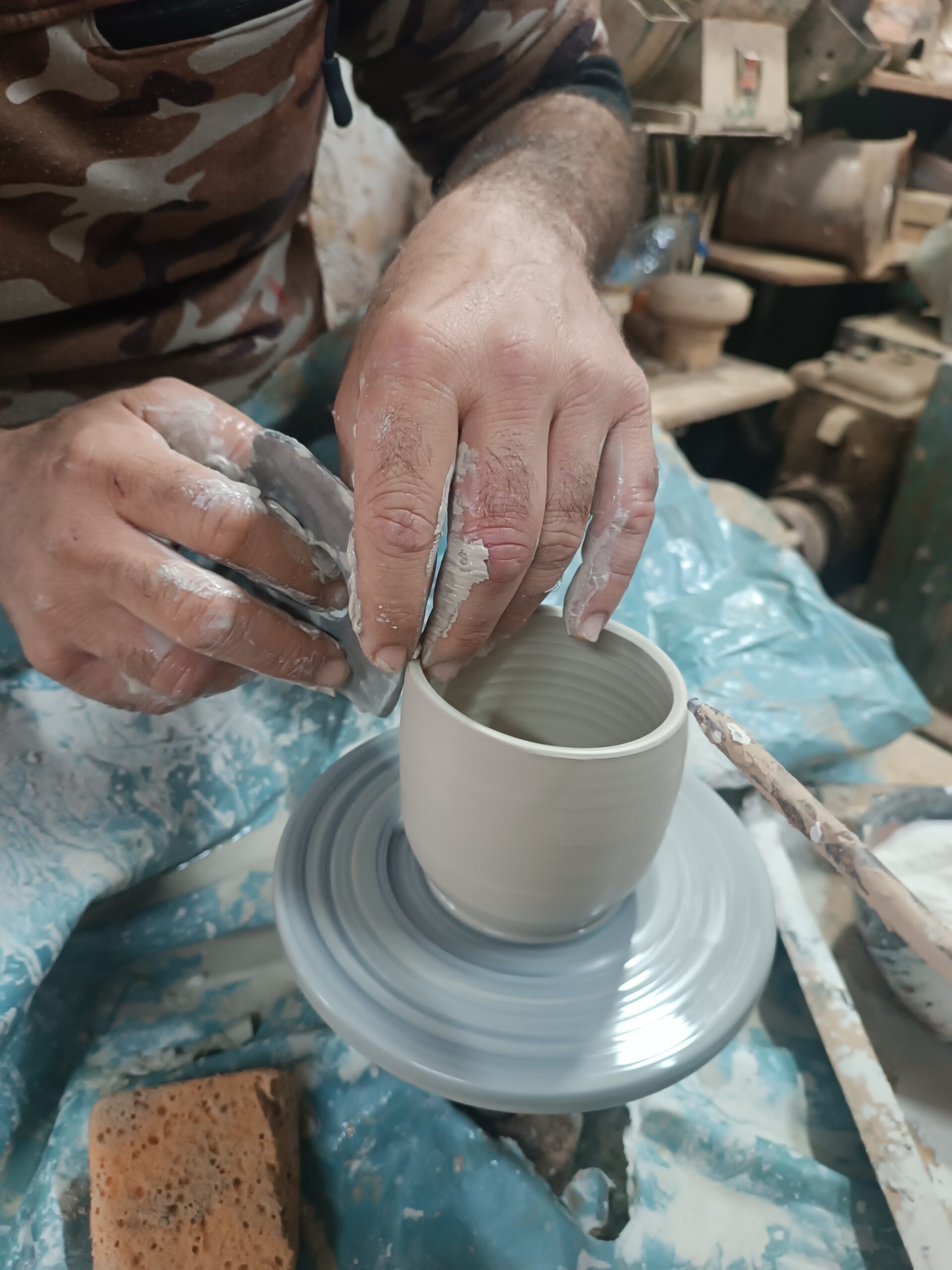 Close-up of a skilled ceramist’s hands working on a piece of GRAMMA artisanal pottery in a traditional Samos workshop.