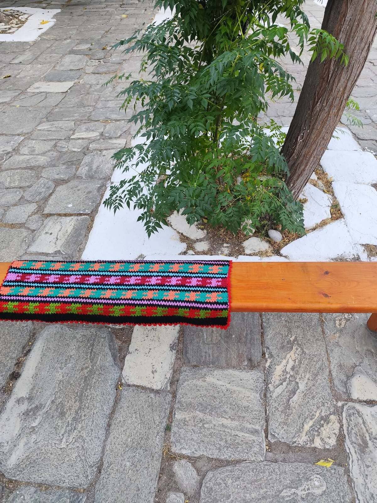 ο σκηνικό της πρώτης μας βιωματικής δράσης. Ένα παραδοσιακό, πολύχρωμο υφαντό στρωμένο στο ξύλινο παγκάκι της πλατείας, συμβολίζοντας το νήμα που ενώνει την ιστορία με το παρόν, λίγο πριν ξεκινήσει ο κύκλος μας.